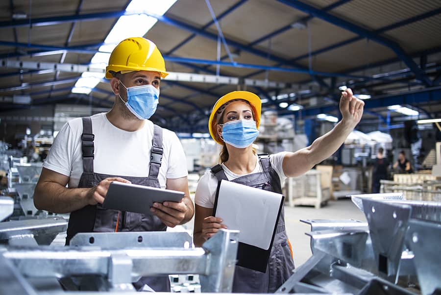 Operarios con casco revisando una línea de producción industrial